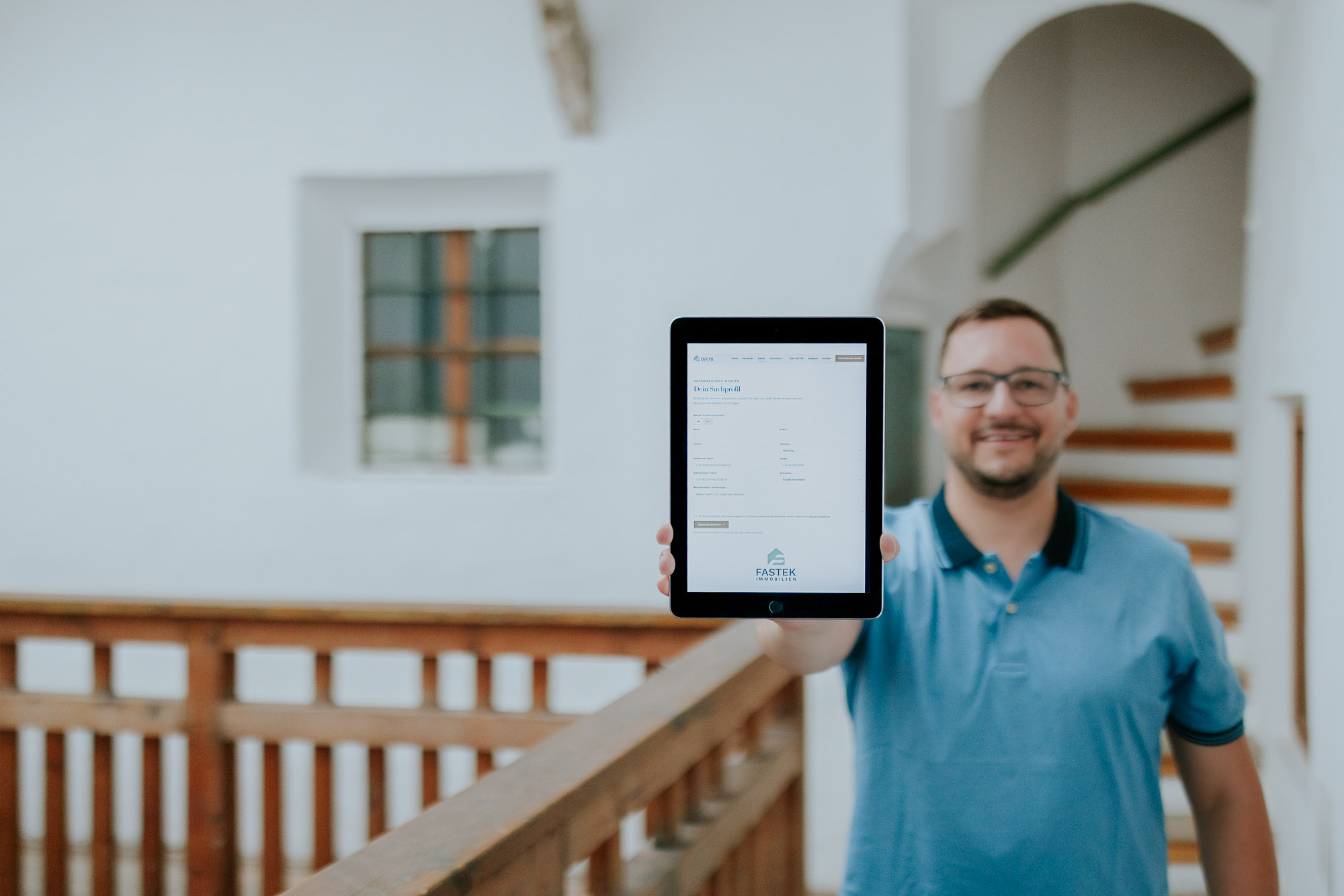 Immobilienberater Fabian hält ein Tablet mit dem FASTEK Suchprofil in die Kamera
