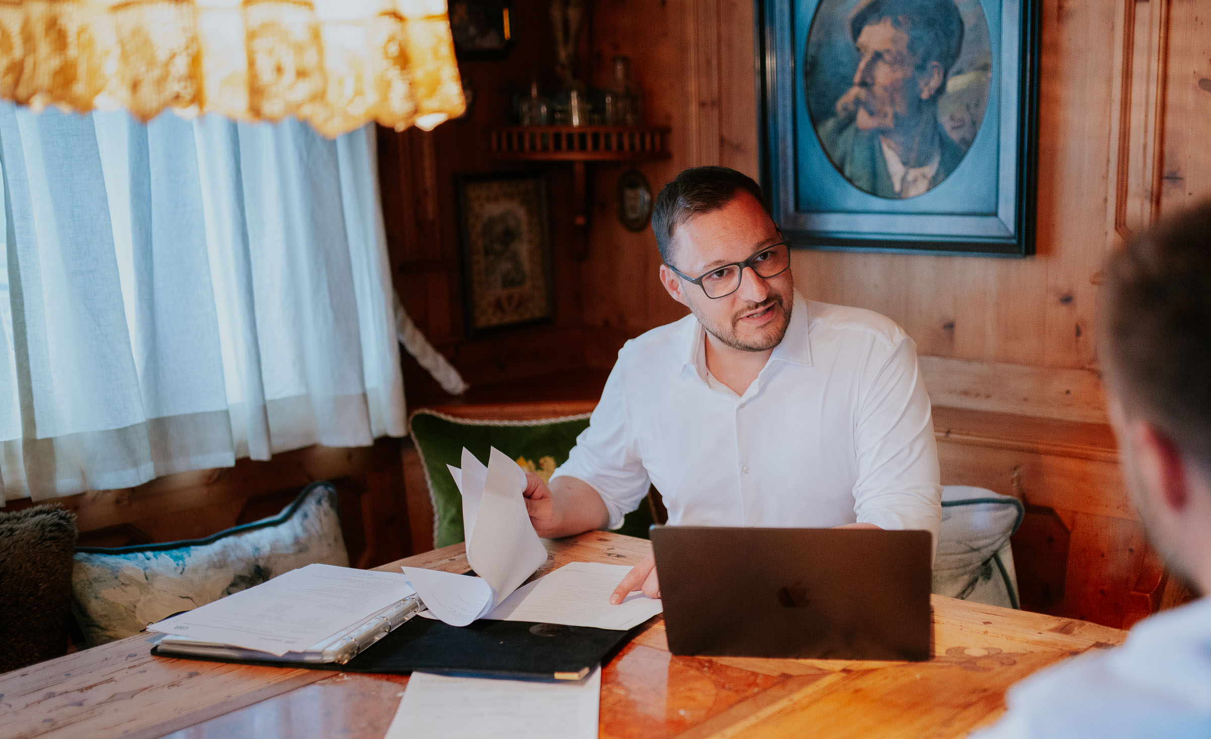 Fabian im Gespräch mit einem Kunden an einem Holztisch mit Laptop und Unterlagen